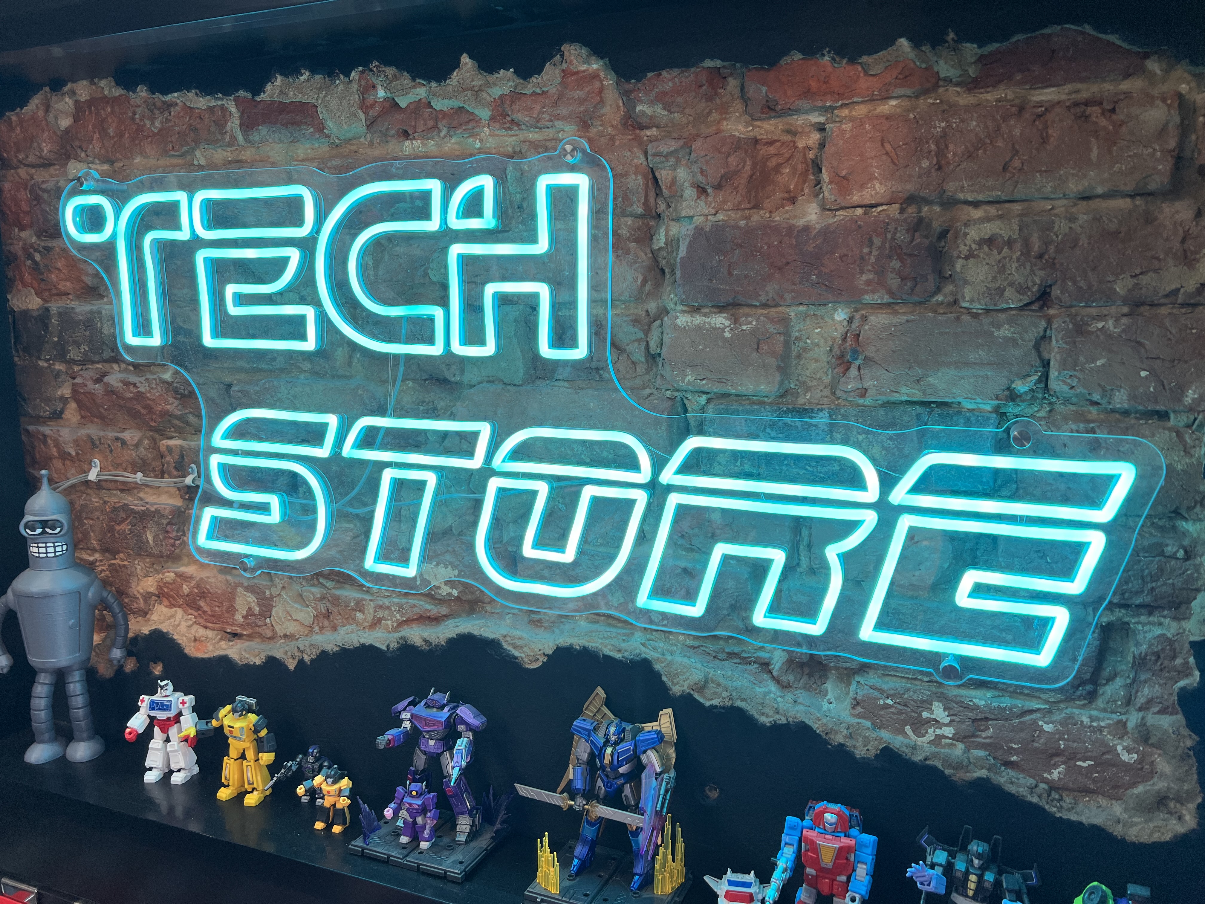 Neon Tech Store sign with action figures on display